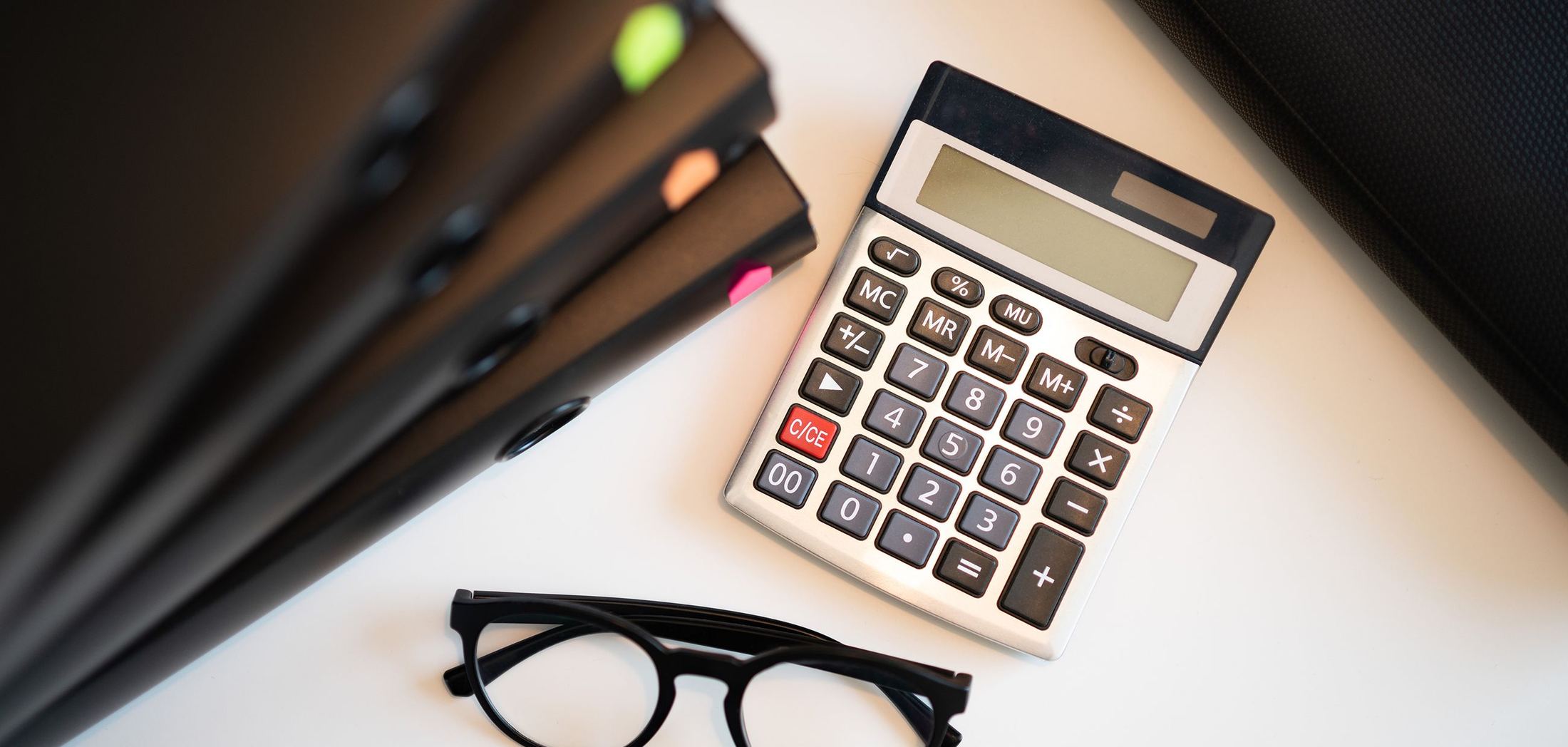 Calculadora, anteojos y carpetas sobre un escritorio